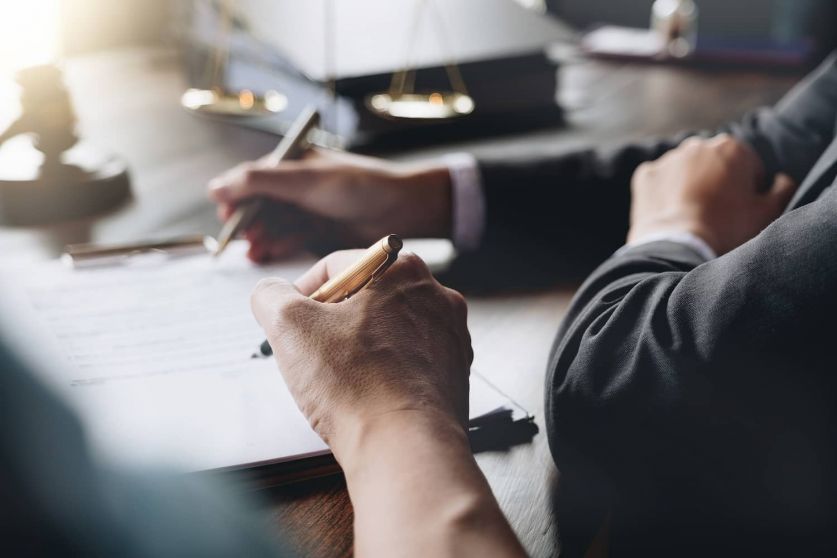 Richterhammer mit Justizanwälten bei einer Teambesprechung in einer Anwaltskanzlei im Hintergrund. Notar mit Klient im Büro