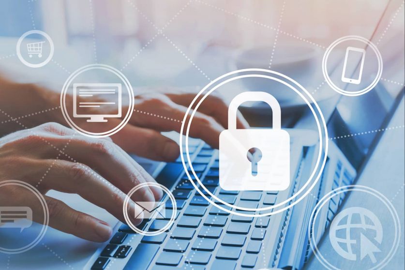 Zwei Hände über der Tastatur eines Laptops. Entsprechende Themen werden anhand von Icons projiziert: Informationssicherheit online, Cybersicherheit und Schutz personenbezogener Daten.